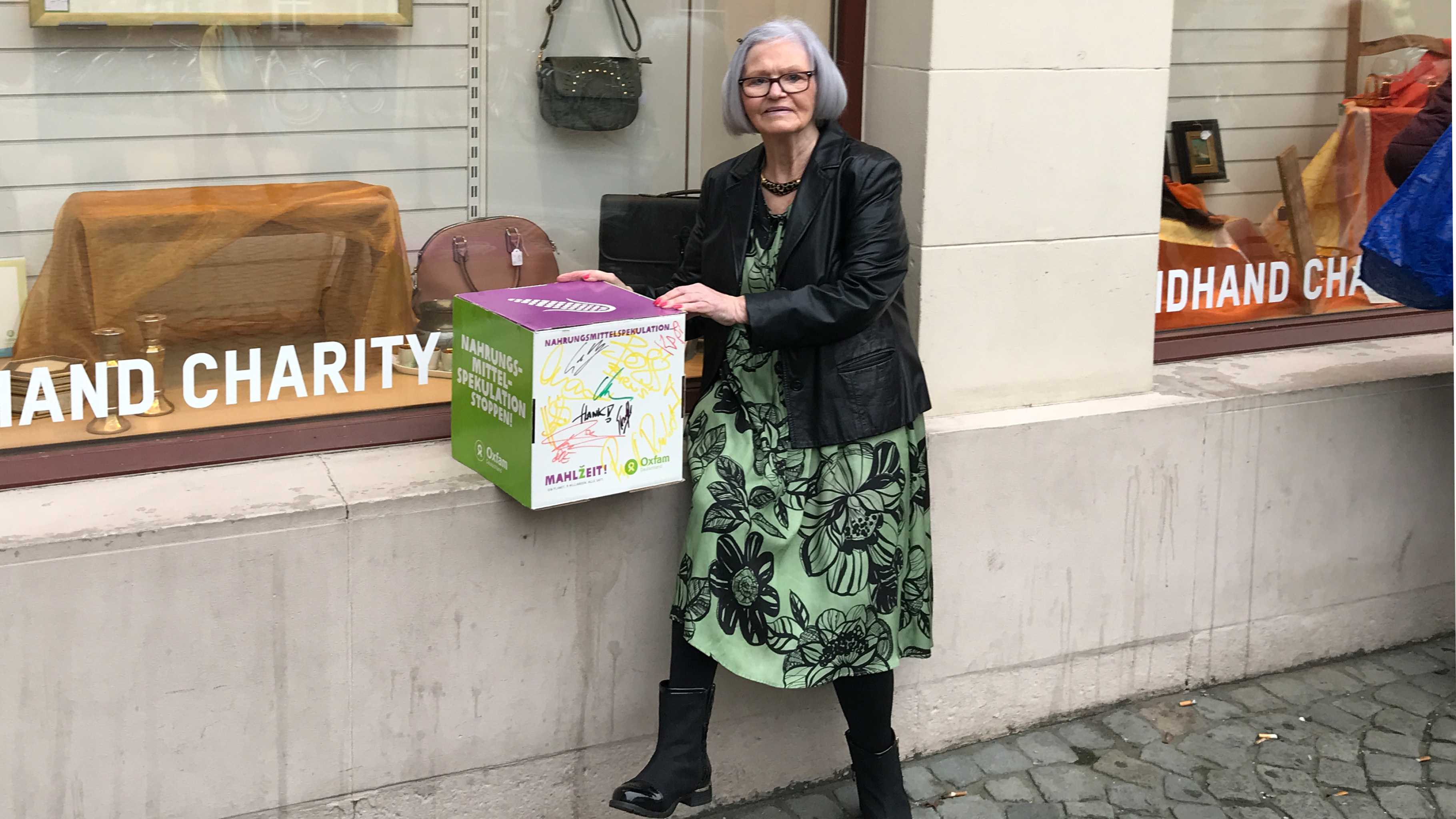 Die Ehrenamtliche Hannelore Neuhaus-Becker mit der von The BossHoss signierten Box vor dem Oxfam Shop Mainz