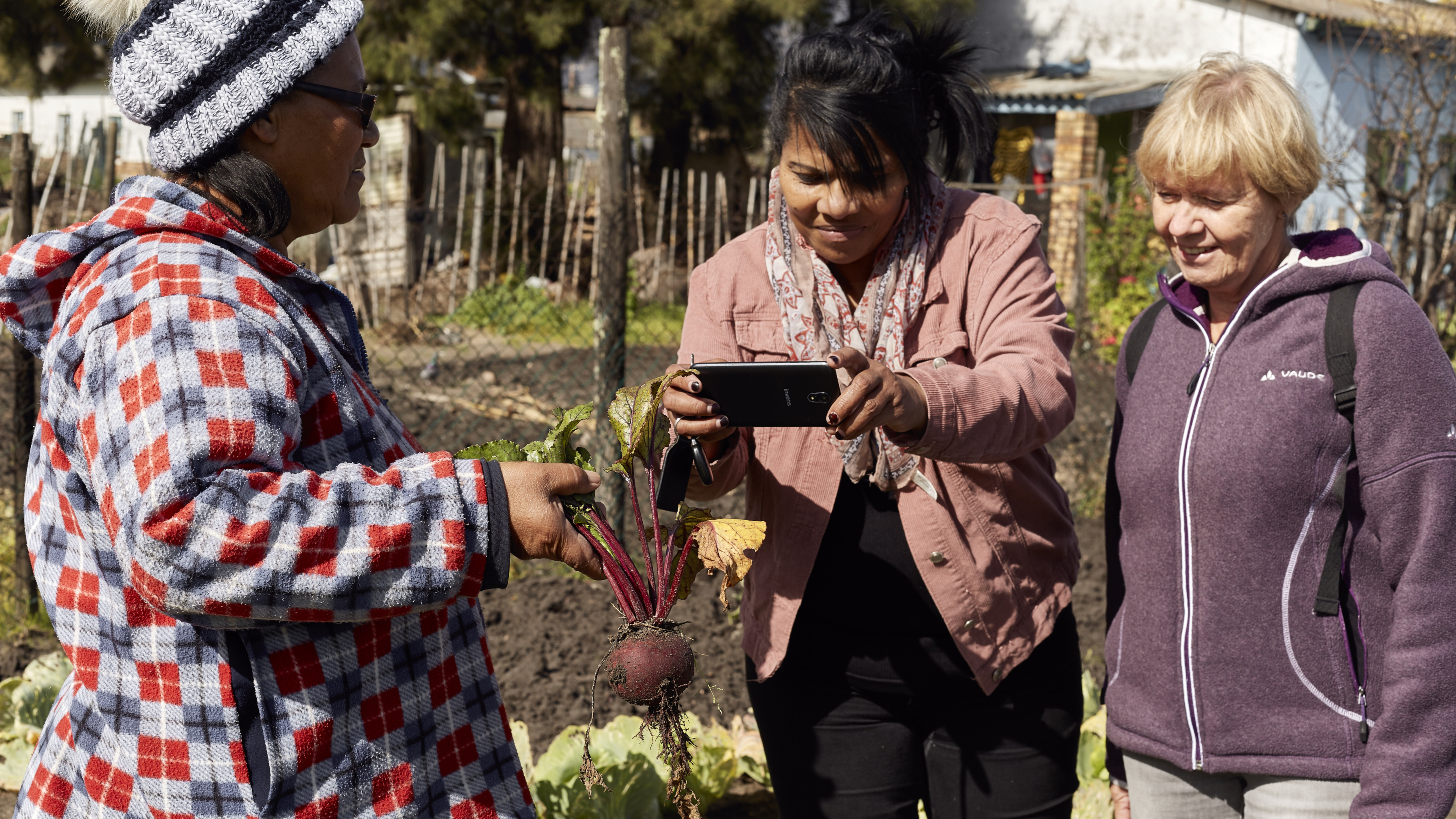 Elizabeth Lieman zeigt Sharon Massena und Gaby rote Bete aus ihrem Garten. 
