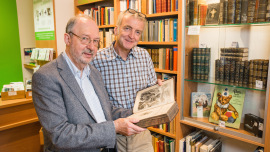 Der Ehrenamtliche Klaus Roland (li) zeigt Dirk Horn ein wertvolles gespendetes Buch.