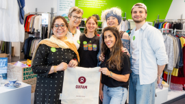 Gruppenfoto der ehrenamtlichen Mitarbeitenden Dipeeka Bhambry und Kathy L. A. (vorne mit Stoffbeutel, von links) sowie Ulrike W., Leonore Richter, Jolanta Cegielka-Kostorz und Jeremias M. (hinten, von links) im Oxfam Shop in Halle/Saale.