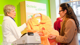 Kundin kauft Winterjacke im Oxfam Shop