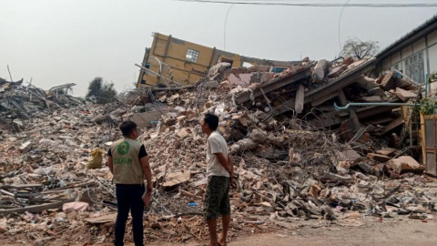 Oxfam-Mitarbeiter im Gespräch mit einem Einwohner über die Verwüstungen in Mandalay: Zwei Personen stehen vor der Trümmern, die das Erdbeben verursacht hat.