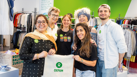 Gruppenfoto der ehrenamtlichen Mitarbeitenden Dipeeka Bhambry und Kathy L. A. (vorne mit Stoffbeutel, von links) sowie Ulrike W., Leonore Richter, Jolanta Cegielka-Kostorz und Jeremias M. (hinten, von links) im Oxfam Shop in Halle/Saale.