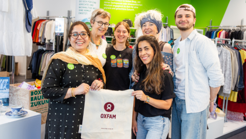 Gruppenfoto der ehrenamtlichen Mitarbeitenden Dipeeka Bhambry und Kathy L. A. (vorne mit Stoffbeutel, von links) sowie Ulrike W., Leonore Richter, Jolanta Cegielka-Kostorz und Jeremias M. (hinten, von links) im Oxfam Shop in Halle/Saale.